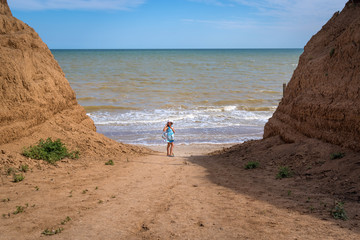 Beautiful seascape. The girl in a dress and a white hat goes down to the sea