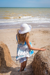 Beautiful seascape. The girl in a dress and a white hat goes down to the sea