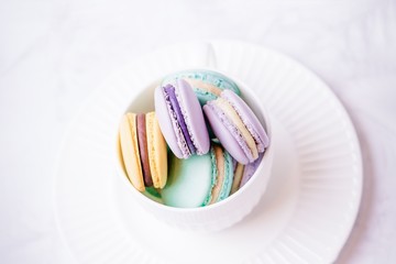 Sweet colourful french macaroons or macaron on white marble background. Top view, copy space
