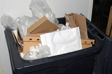 Full trash can. Filled with cardboard, plastic and paper without proper recycling.