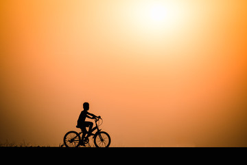 Fototapeta na wymiar Silhouette boy cycling on sunset background