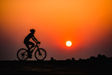Fototapeta premium Silhouette man cycling on sunset background