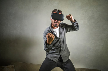 excited man wearing virtual reality VR goggles headset experimenting 3d illusion playing fight or boxing video game enjoying punching isolated on grunge background