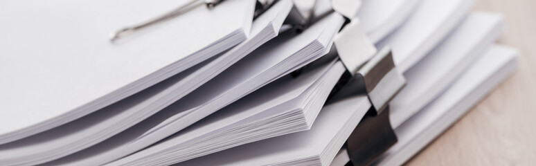 panoramic shot of stacks of blank paper with metal paper clips