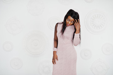 Fashionable african american model woman in pink brilliant evening dress posed against white...