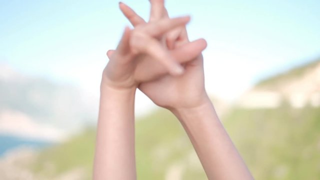 Girl's hands slow dancing moves closeup on brurred valley background