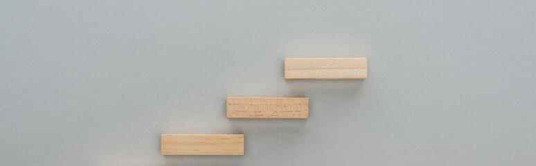 panoramic shot of wooden bricks symbolizing career ladder isolated on grey