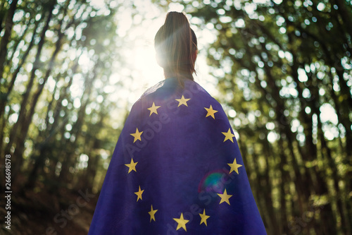 Child teenager girl at nature background an European Union flag on her shoulders