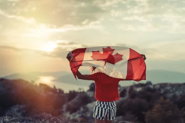 Fototapete Kanada Glückliches Kind im Teenageralter, das die Flagge Kanadas schwenkt, während es bei Sonnenuntergang läuft