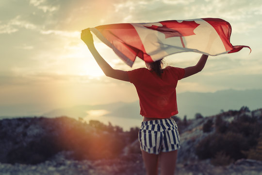 Happy child teenage girl waving the flag of Canada while running at sunset
