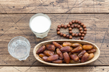 Dried dates fruits on a branch, a glasses of water and milk on a wooden table. Traditional fast breaking, Muslims evening meal during holy Ramadan