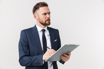Serious businessman posing isolated over white wall background holding clipboard.