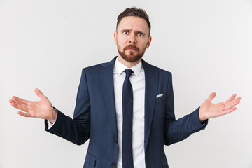 Shocked emotional young businessman posing isolated over white wall background.