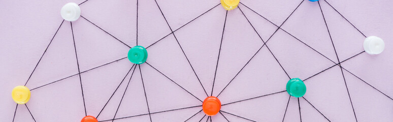 panoramic shot of colorful push pins connected with strings Isolated On pink, network concept