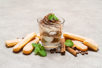 Classic tiramisu dessert in a glass and savoiardi cookies on concrete background