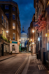 Blick durch eine kleine, beleuchtete Straße in London auf die St. Pauls Kathedrale am Abend