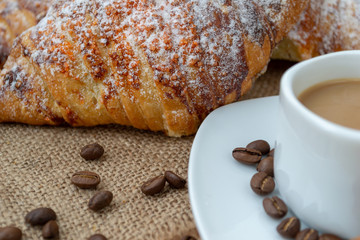 Croissants and coffee with cinnamon on a wooden Board. Hardwood worktop as a background.