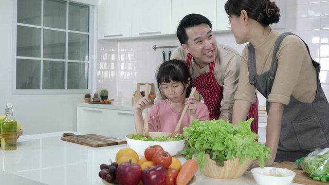 Asian family cooking breakfast in kitchen at home together. Concept of happy family, modern kitchen, food and drink.