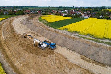 Aerial drone view on excavator loading sand on tipper truck.