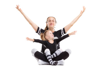 Fototapeta na wymiar Portrait of healthy family of mother sitting in yoga pose with little daughter and raising hands isolated at white background.