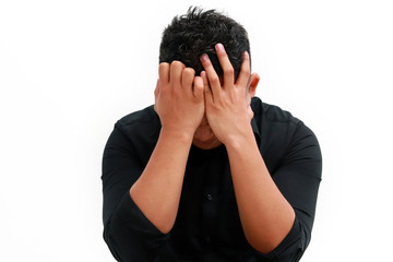 Young man covers his face with his hands in grief or pain.