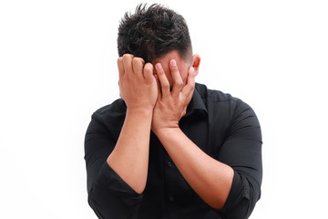 Fototapeta premium Young man covers his face with his hands in grief or pain.