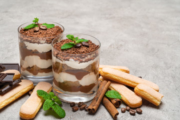 Classic tiramisu dessert in a glass and savoiardi cookies on concrete background