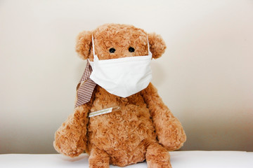 brown soft toy bear sick with a bandage on his nose and a medical thermometer