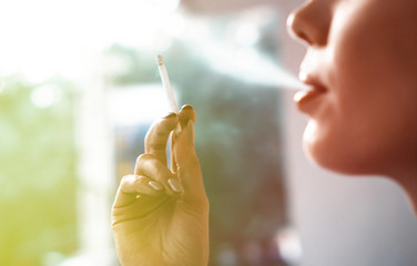 Beautiful woman smoking a cigarette outdoors close up