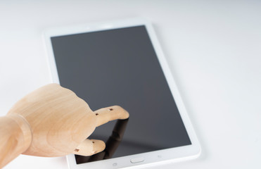 Wooden hand touching a white tablet