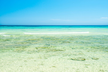 White sand beach and clear sea water under blue sky
