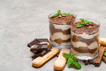 Classic tiramisu dessert in a glass and savoiardi cookies on concrete background