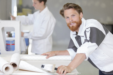 Obraz premium male worker smearing wallpaper with glue