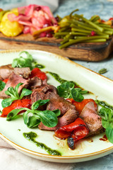 Carpaccio with sauce and spinach. Beautiful serving dishes. Light background. Restaurant menu