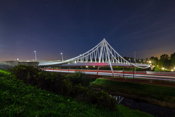Suspension bridge at night under moonlight with light trails