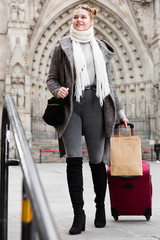 Cheerful young girl in scarf with baggage