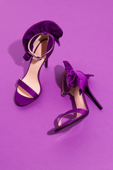 Purple high heels on violet monochrome backgroung with bows