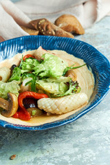 Vegetable salad with squid. Beautiful serving dishes. Light gray background. Restaurant menu
