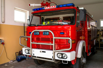 The front of the truck of an old Polish fire truck with visible blue light signals, water cannon and the Polish word "STRAZ".