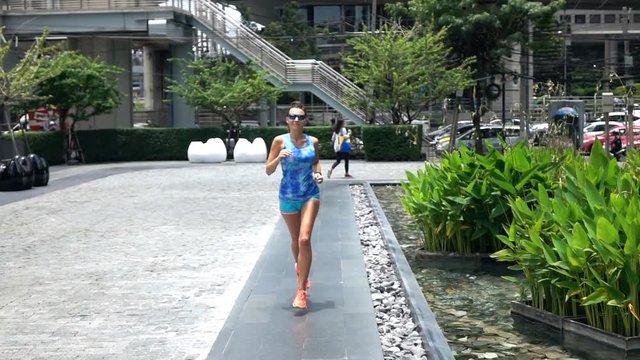 Young, fit sexy woman jogging in the city, super slow motion