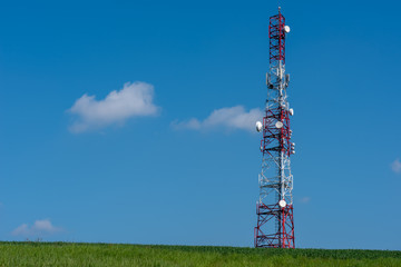Telecommunication tower on the green field against clean blue sky