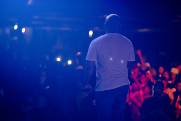 Rapper standing on stage with audience watching him