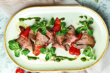 Carpaccio with sauce and spinach. Beautiful serving dishes. Light background. Restaurant menu