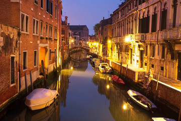 Venice night cityscape with boats in canal, Italy. Venice street illuminated lanterns