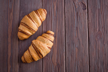 Croissants on a brown wooden table. Free space for text. View from above. View from above.