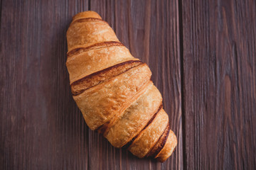 Fresh croissant on a brown wooden table. View from above. View from above