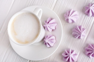 white cup of coffee, cappuccino on a white background with lilac meringues