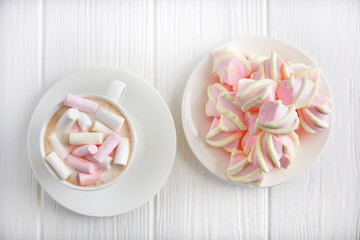cup of cappuccino and marshmallows on a white wooden background