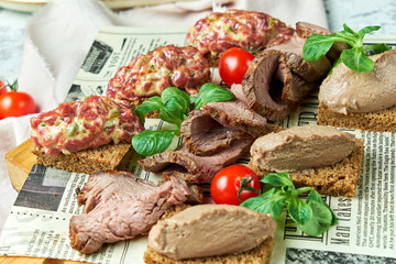 Cold meat snacks. Beautiful serving dishes. Light gray background. Restaurant menu