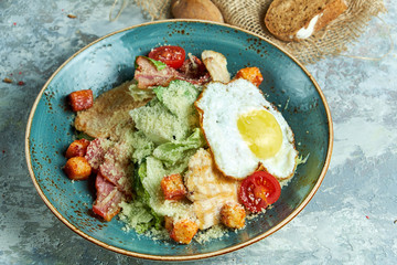 Caesar salad with fried egg. Beautiful serving dishes. Light gray background. Restaurant menu